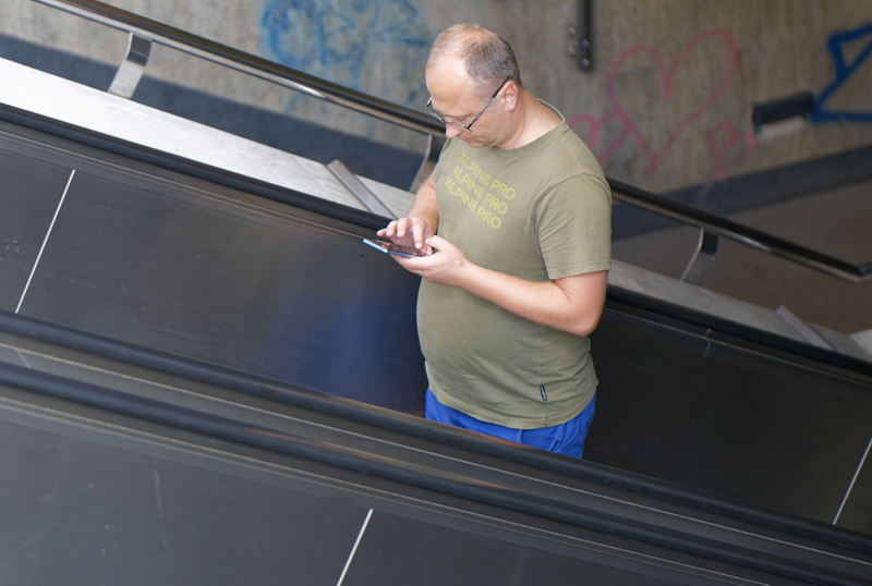 10 - An individual standing on an escalator while using a smartphone, highlighting the importance of not getting distracted for safety.